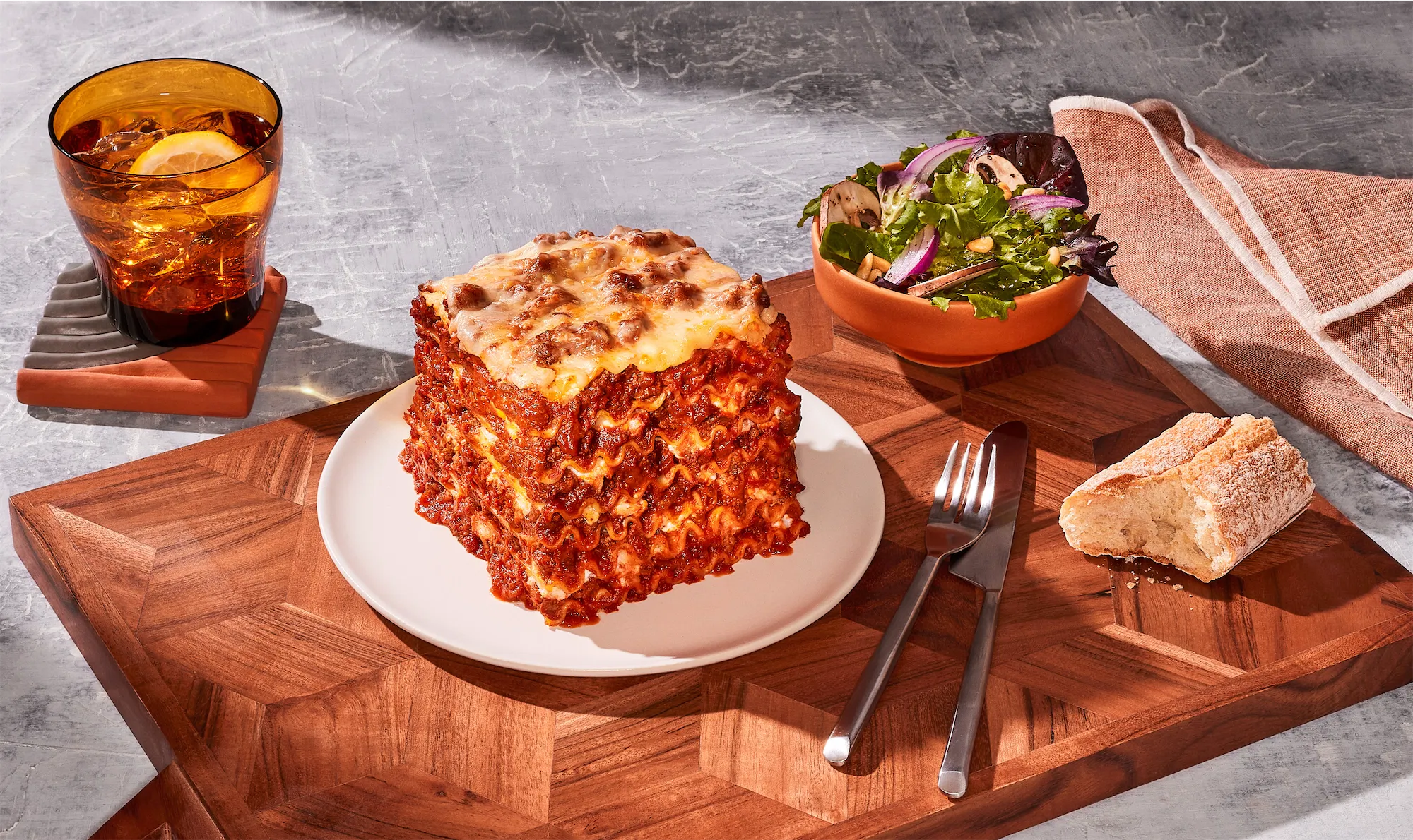  ragu brand stacked lasagna on white plate with side salad and bread