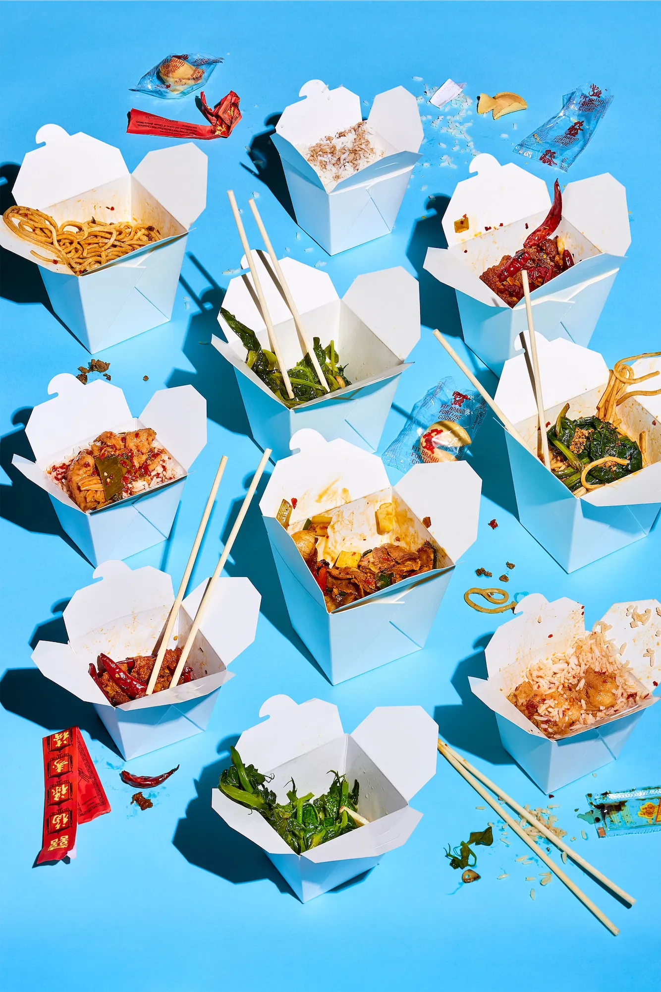 multiple take out boxes with asian food and chopsticks on blue background