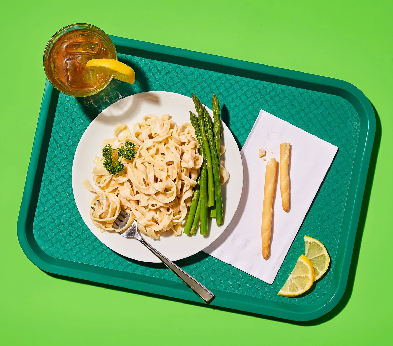 overhead schene of green diner canteen tray and a plate of noodles with asparagus