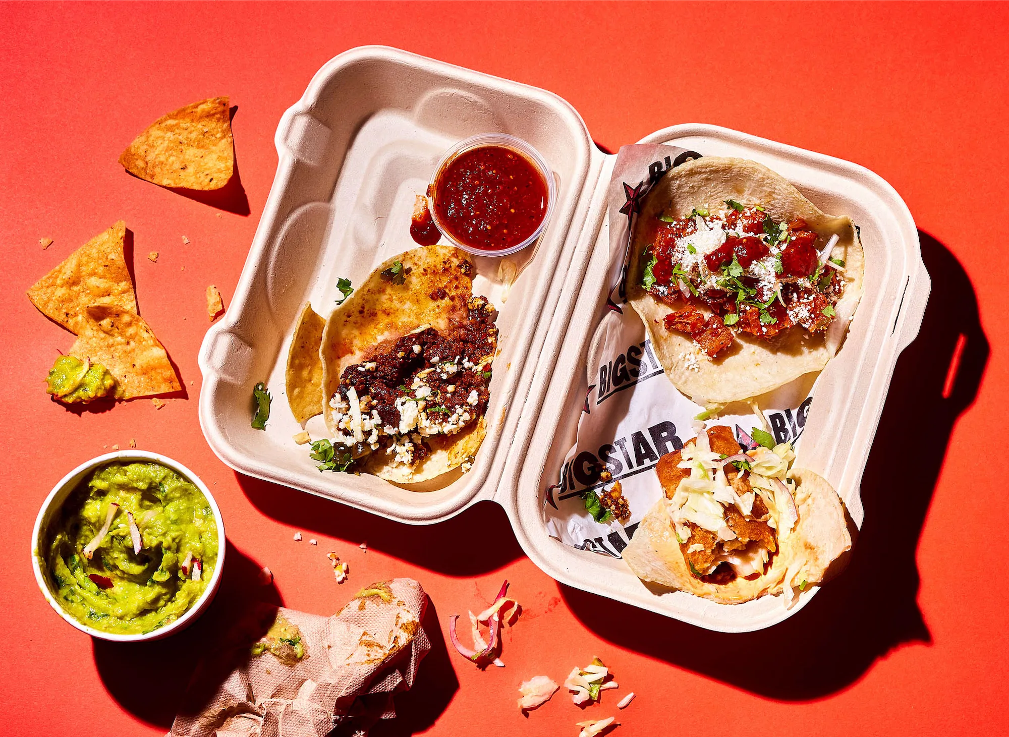 a messy scene with chicago big star tacos in a take out box on orange surface