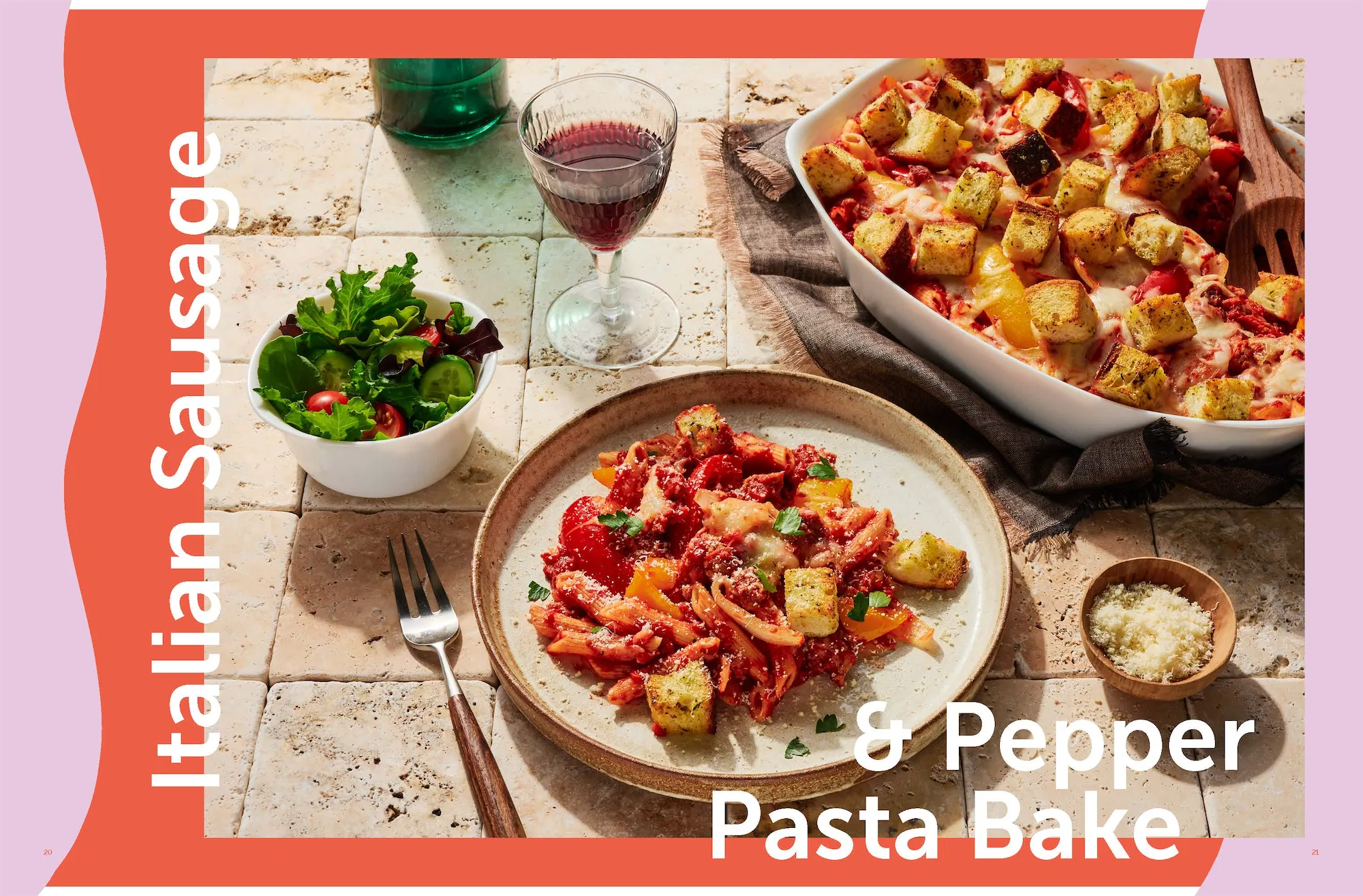 italian sausage and pepper pasta bake recipe served on a plate from a baking dish with a side salad and a galss of red wine
