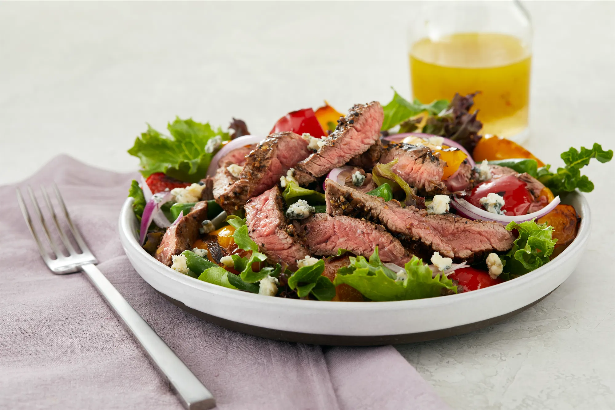 national beef brand steak salad rare meat with lettuce goat cheese a fork and a glass of beer