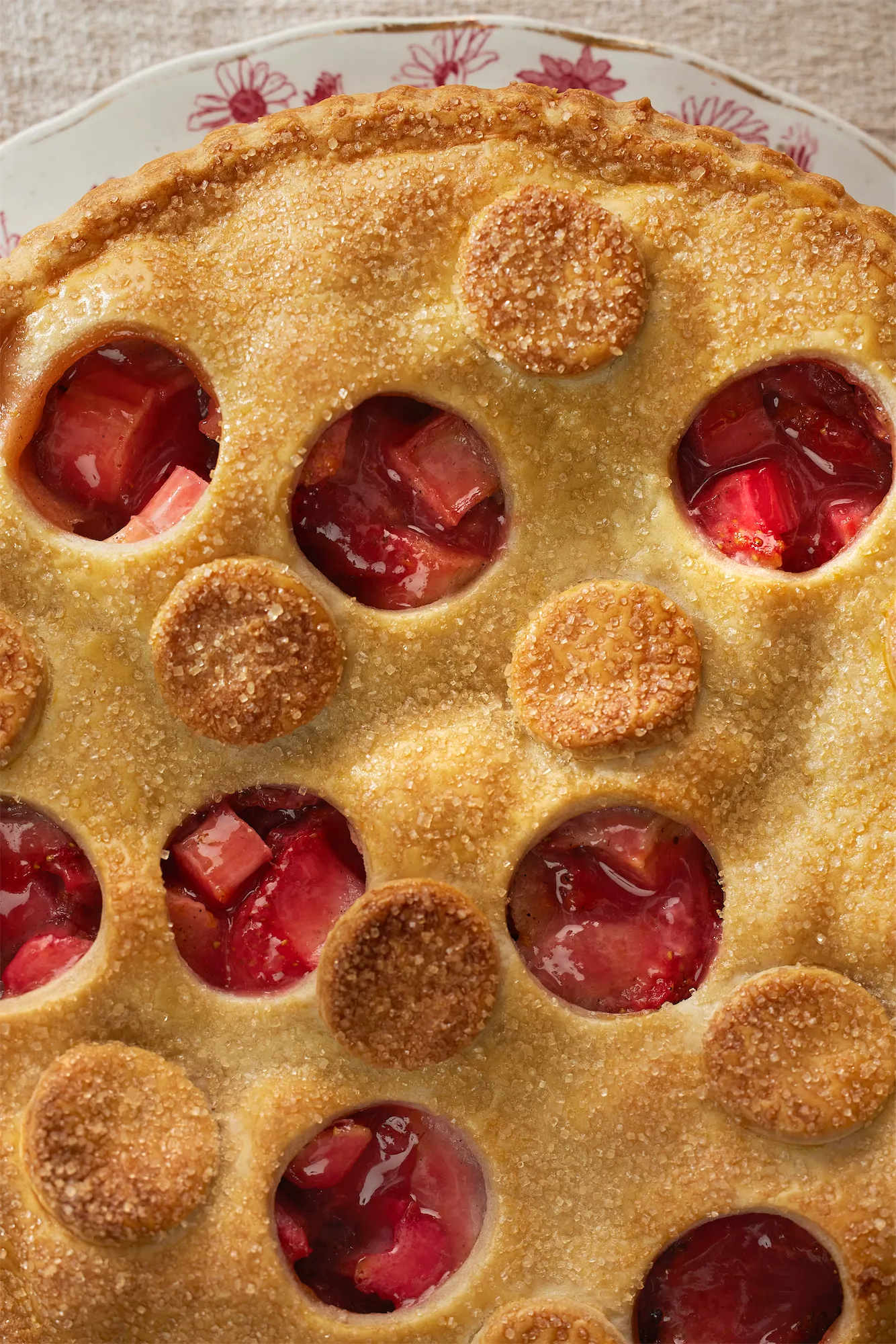 an overhead of strawberry rhubarb pie with round pastry cut-outs and a sugary crust.