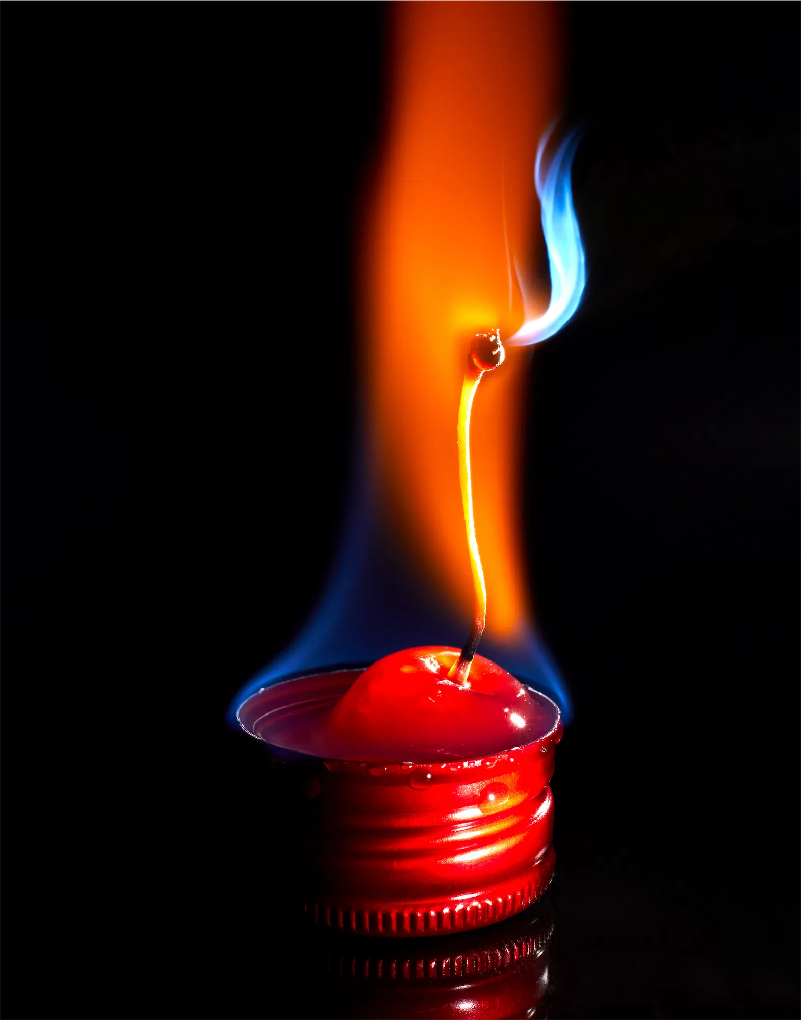flaming cherry in a red bottle cap on balck background