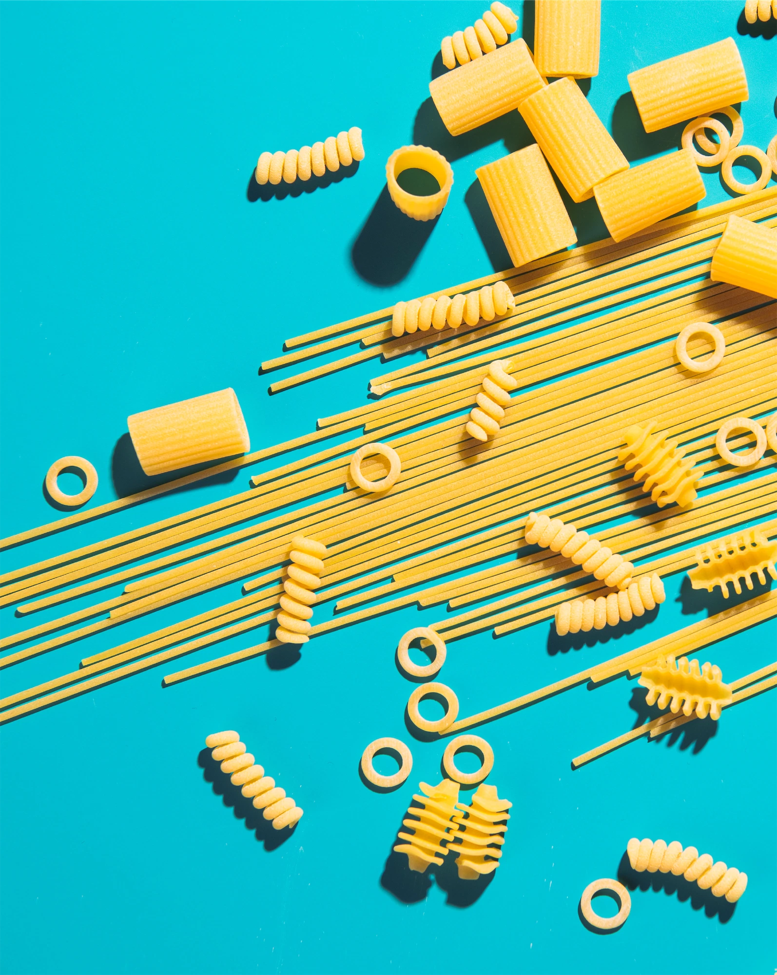 an assortment of yellow pasta shapes on a bright blue background