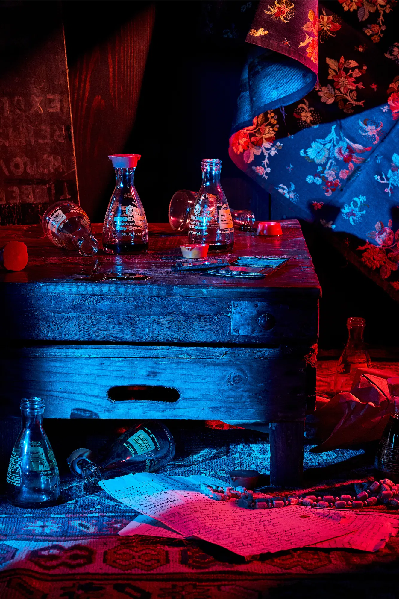 a glowing blue and red scene with soy sauce bottles on a wooden box and silk asian style fabric