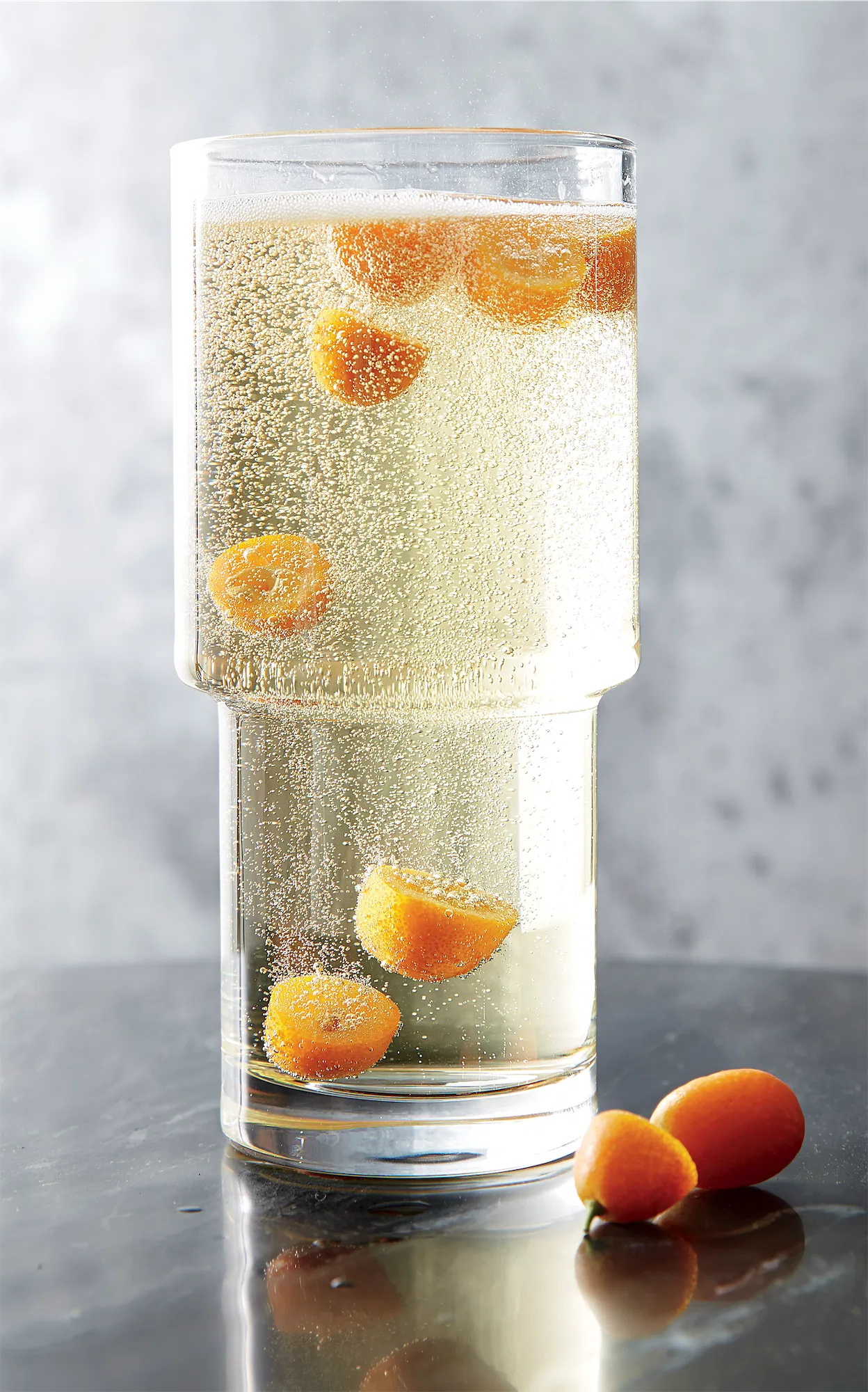crate and barrel stack barware glass filled with champagne and floating kumquats