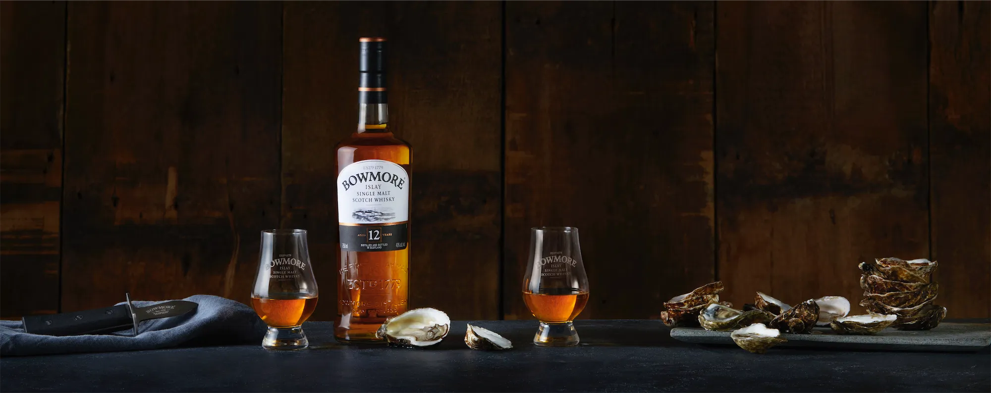 a panoramic of Bowmore brand white label whiskey and shucked oysters