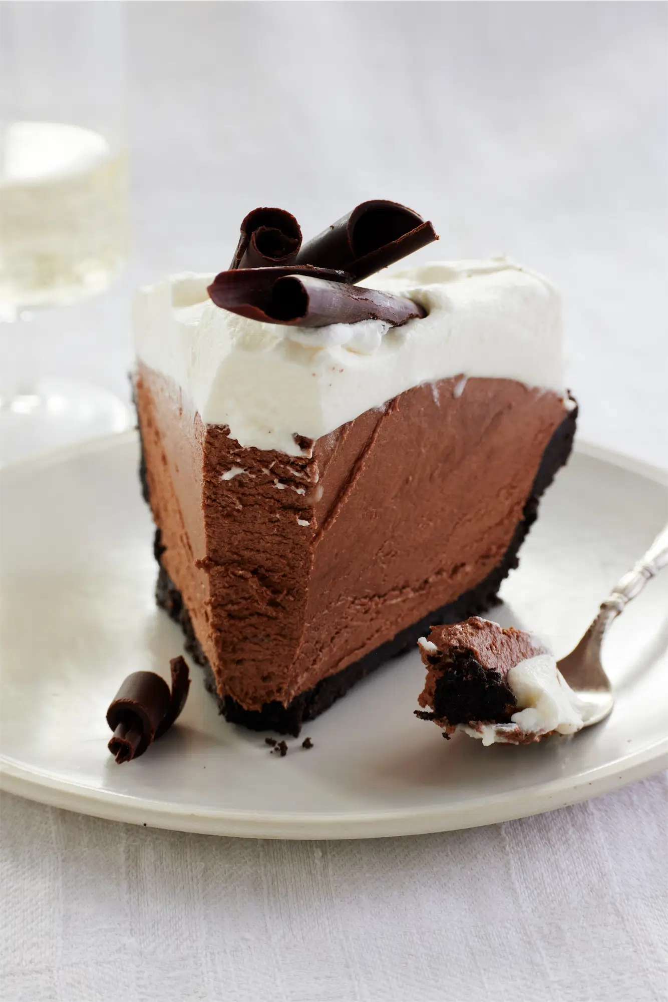Creamy french silk pie cake topped with chocolate curls on a white plate