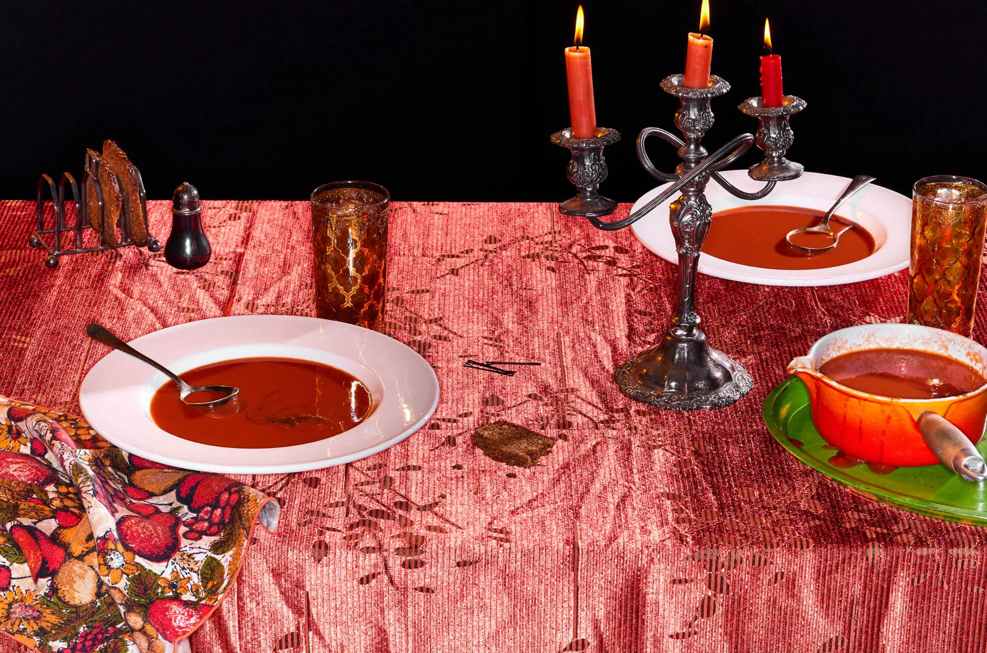 bowls of tomato soup on a pink tablecloth with a candelbra waiter there's a hair in my soup