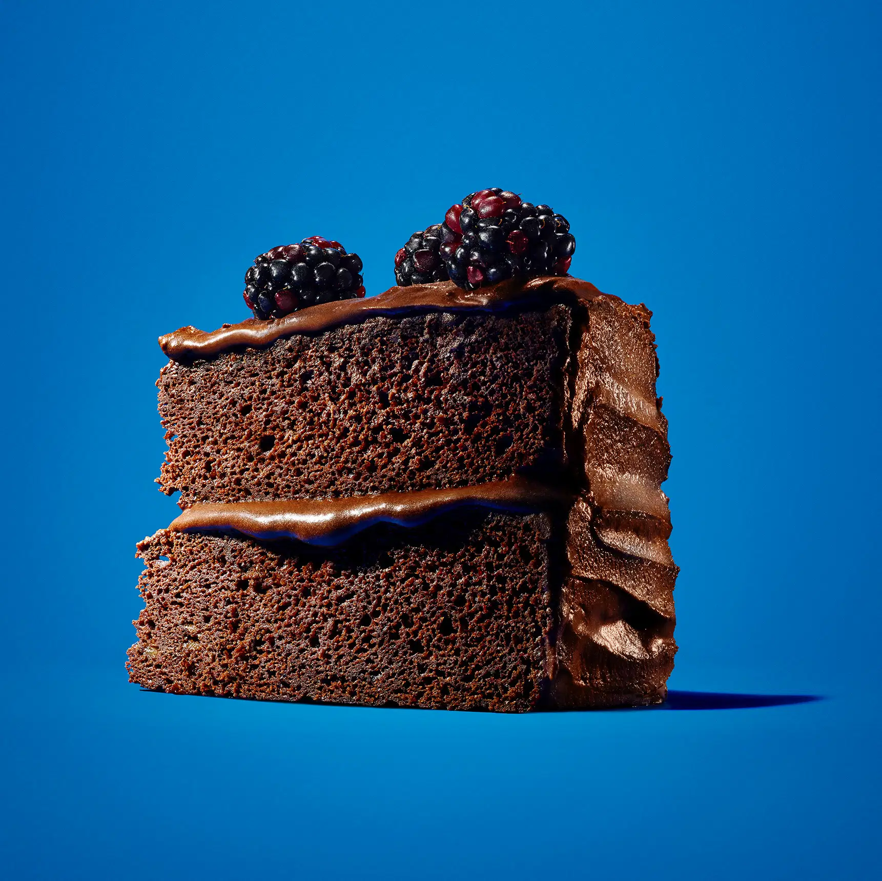 heroic angle two layer chocolate cake with frosting on blue background for Kraft
