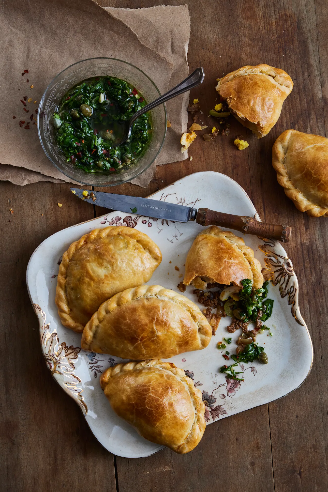 empanadas on a plate some broken open with green salsa