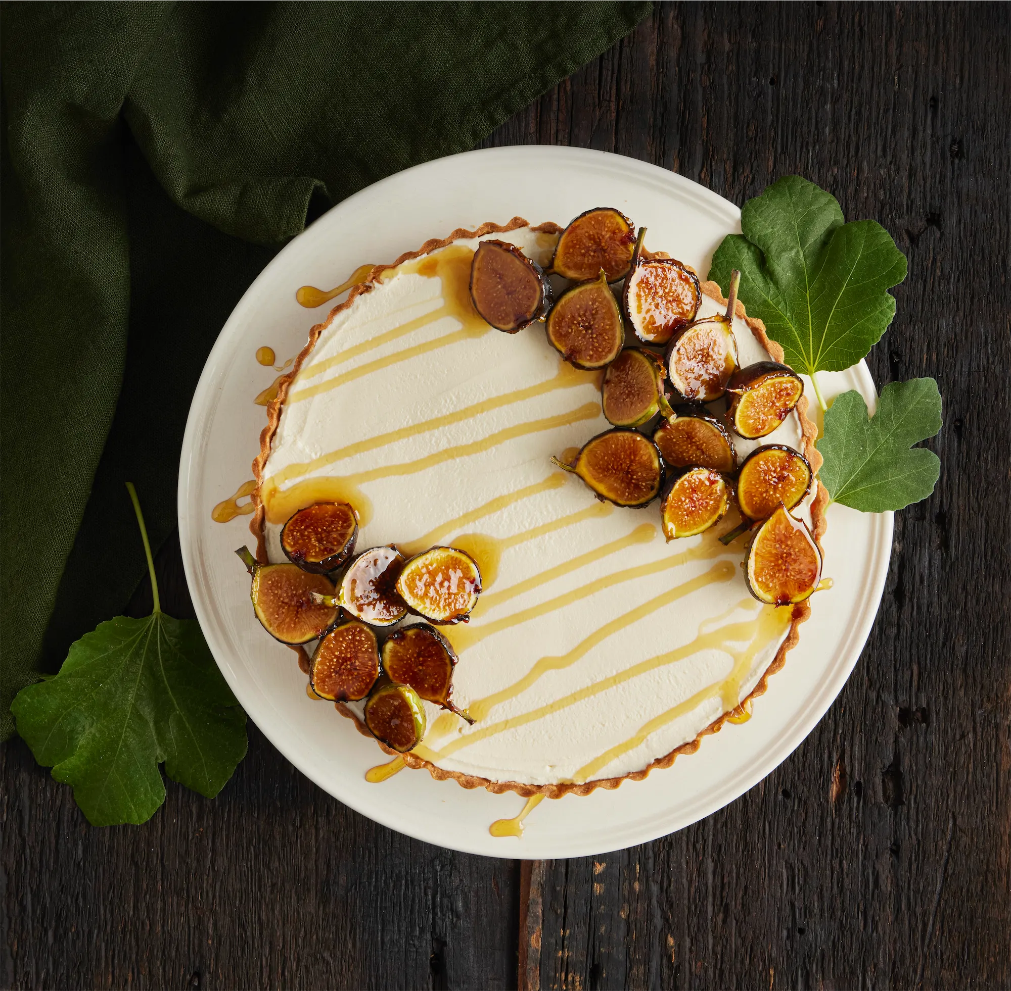 fig cheesecake with cut figs covered in syrup and fig leaf garnish