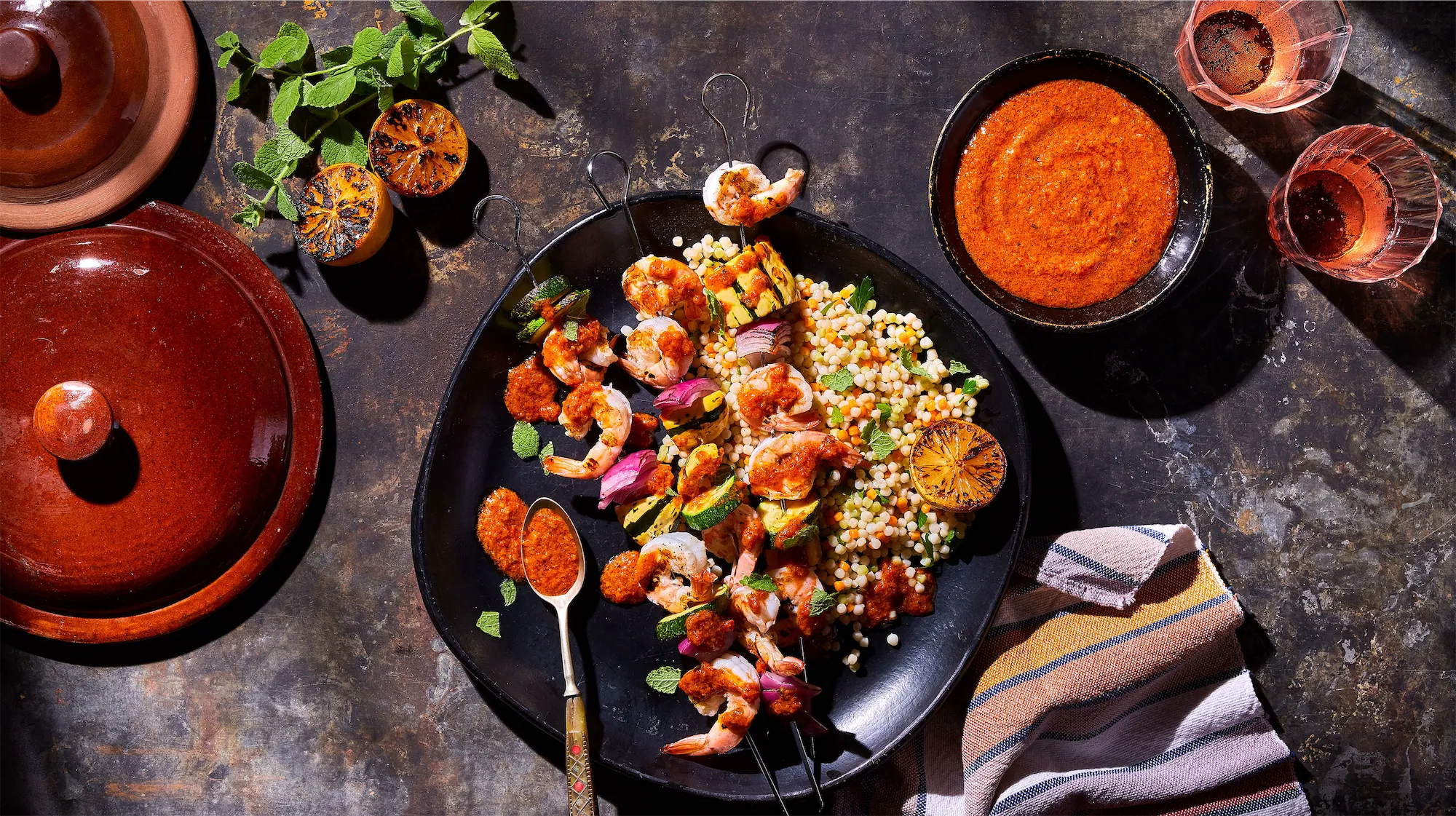 ustic metal surface with black plate shrimp receipe with couscous and red salsa rose wine and terracotta