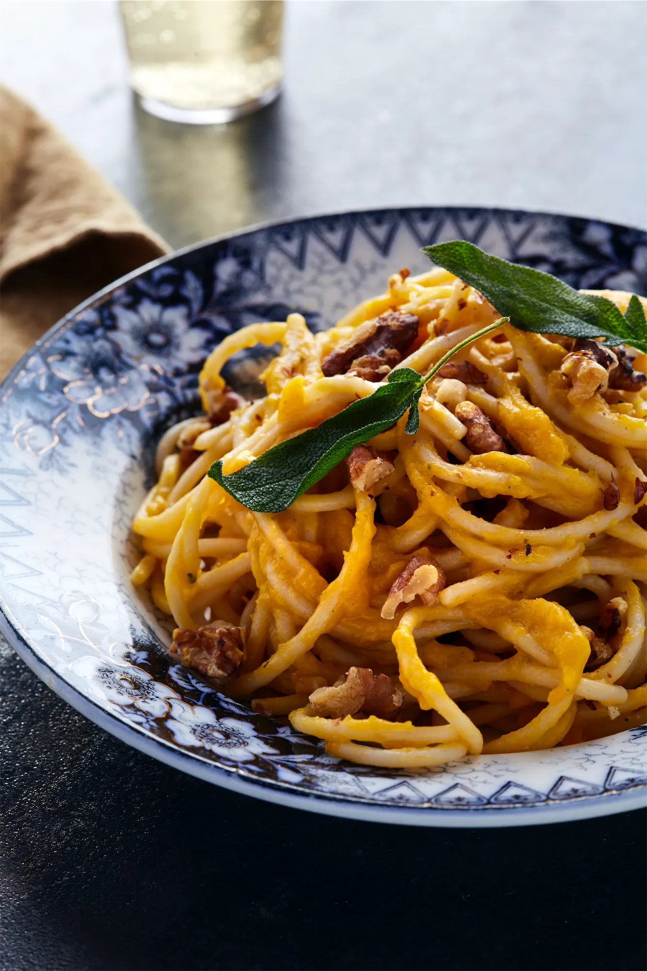 antique blue and white bowl with spaghetti recipe and fried sage leaves