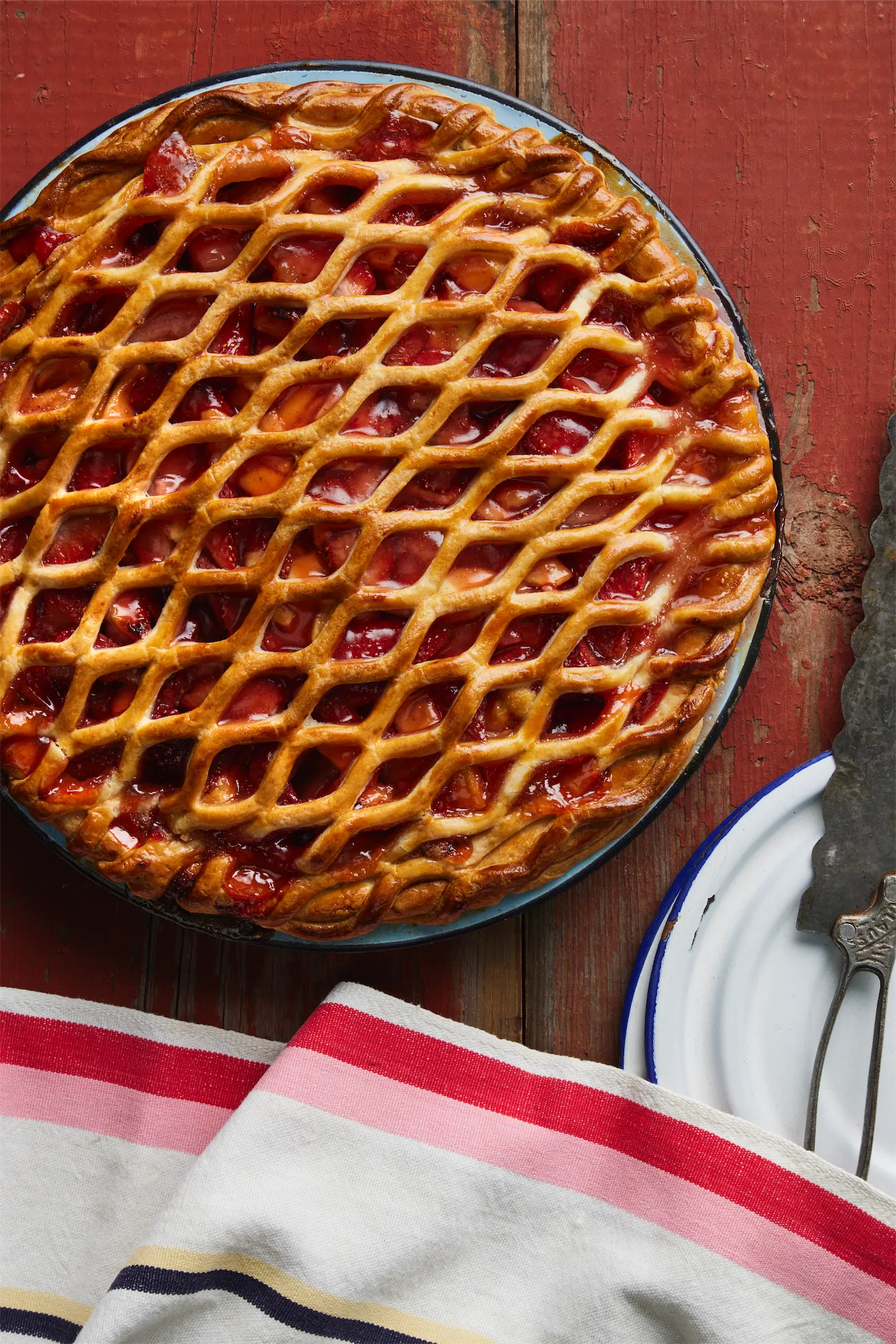 guava pie with a lattice pastry top on a red background and striped pink napkin