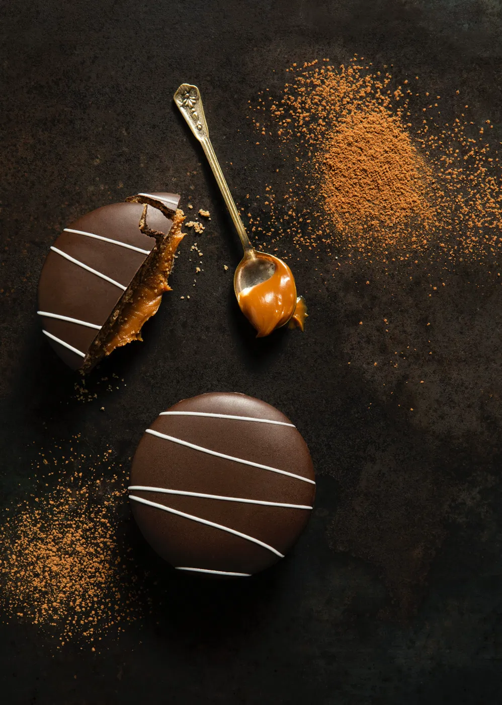 Argentina alfajores chocolate cookies with caramel on dark background with cinammon