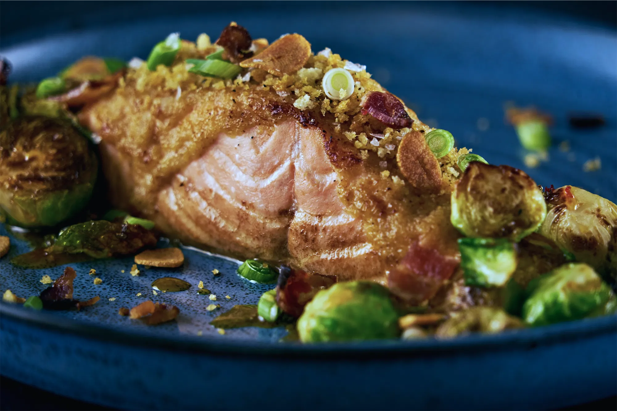 Miso salmon filet with roasted brussels on a blue plate
