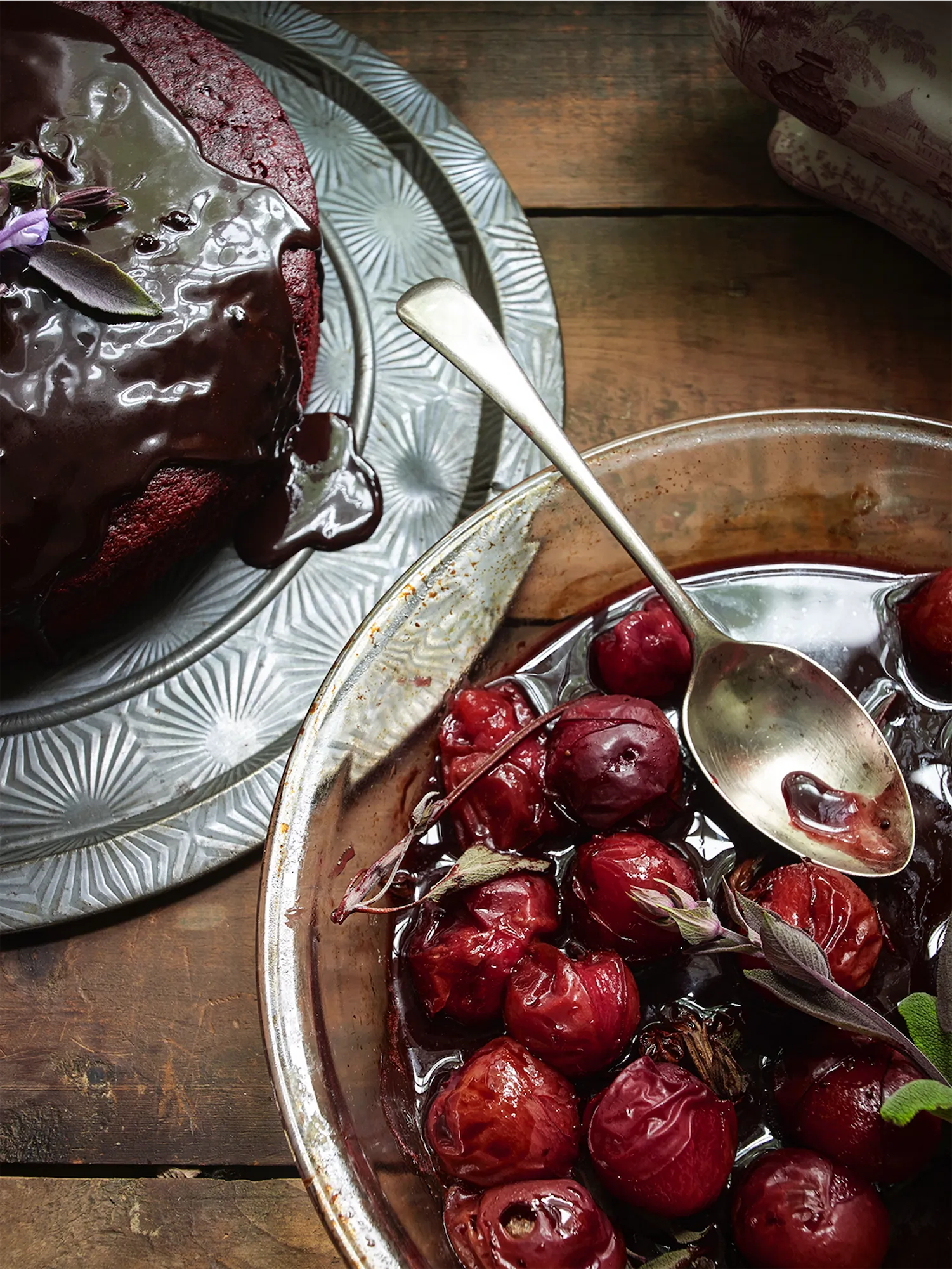 glass pyrex of roasted plums with a cake on a metal tray
