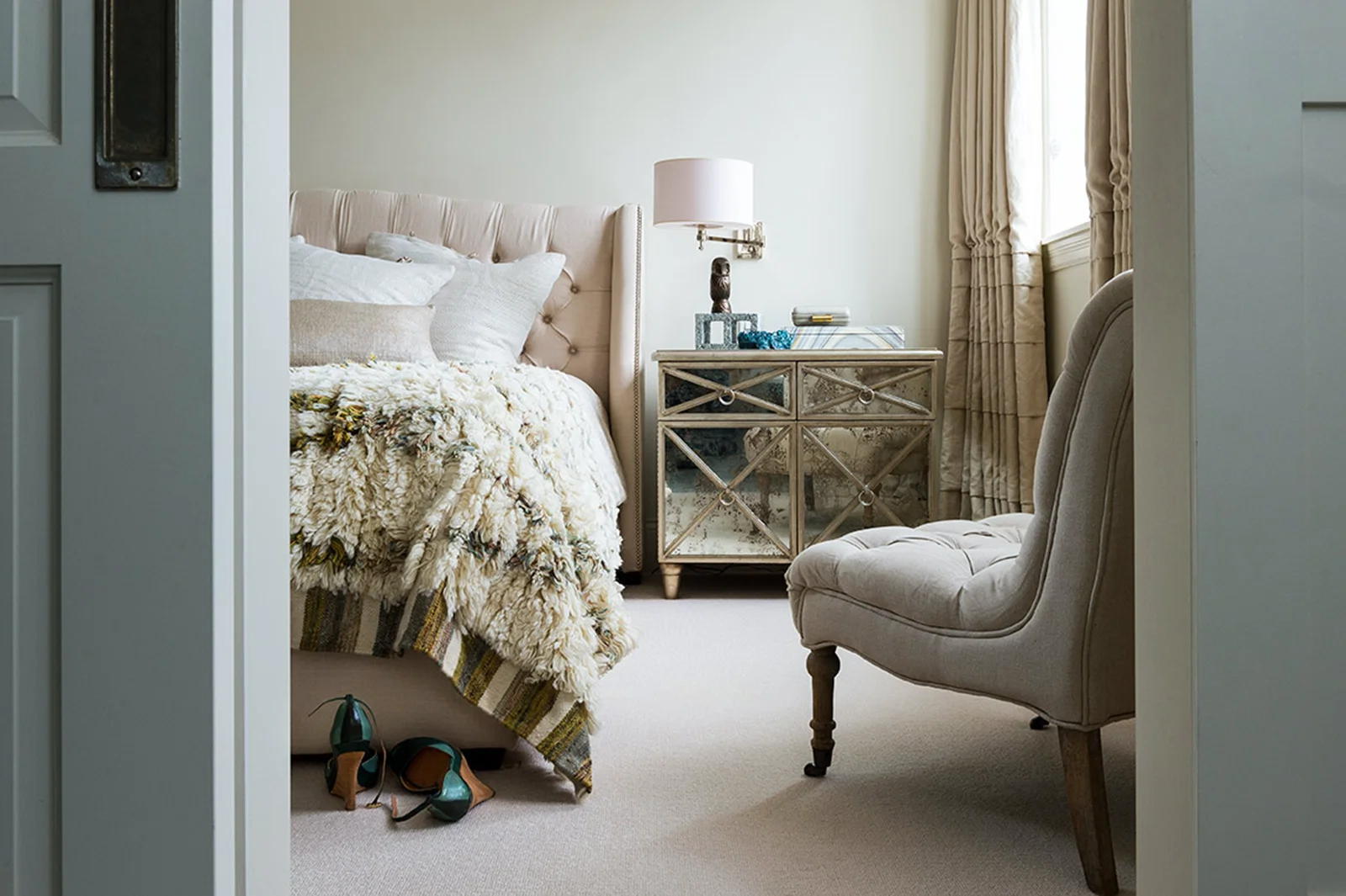Chicago magazine feature tasteful interior cream and beige bedroom scene with mirrored nightstand slipper chair heavy wool bed throw
