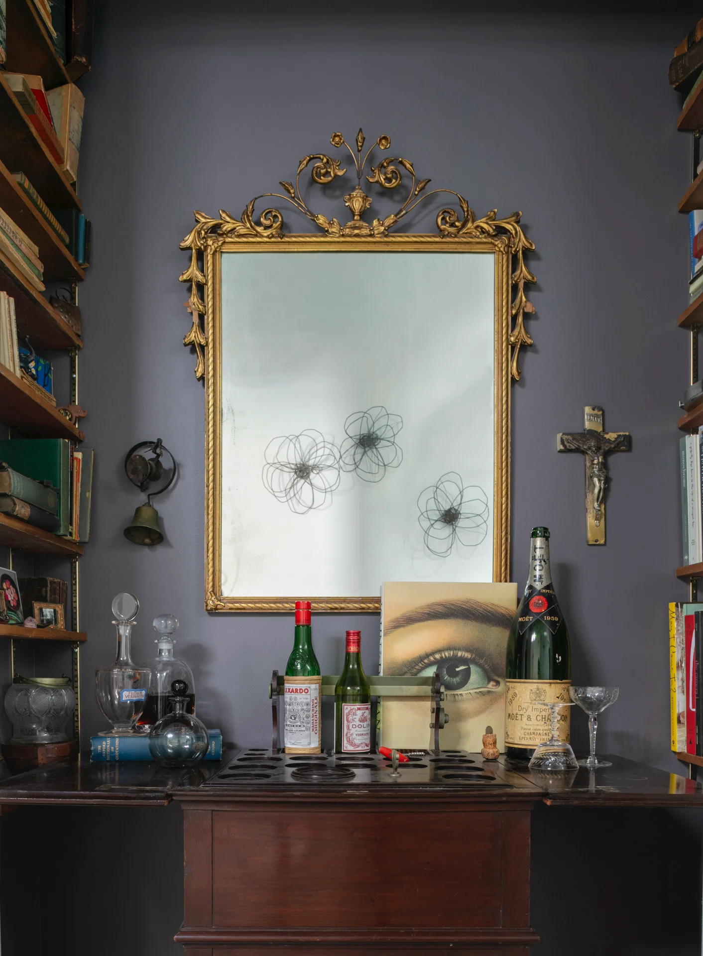 interipr scene cocktail bar assoretd bottles gilt mirror john derian crucifix school bell purple wall moet et chandon asprey
