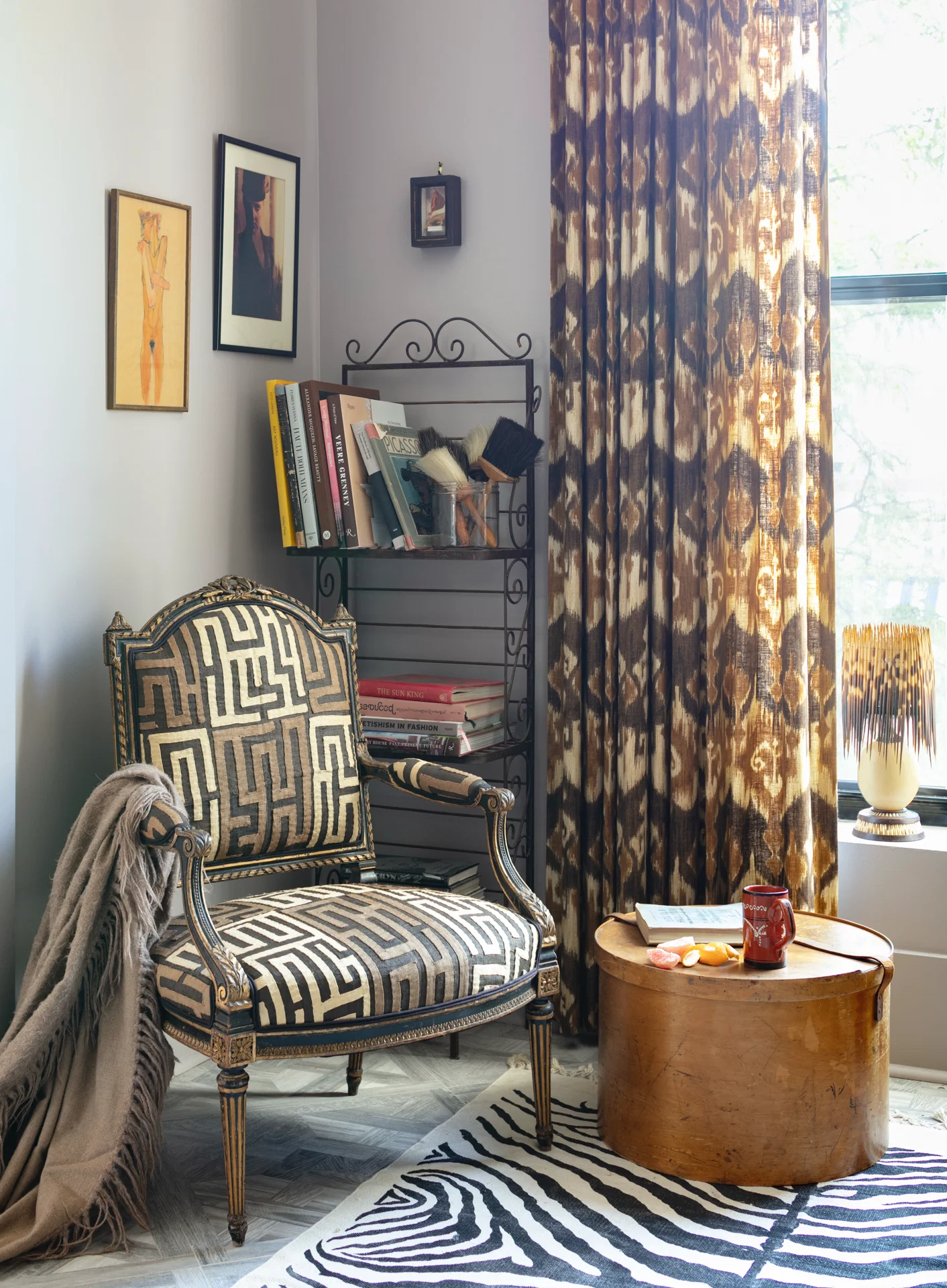 interior scene mudcloth upholstered chair bookshelves animal print rug porcupine lamp